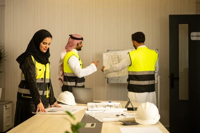 متابعة تنفيذ الخطط الهندسية الموضوعة، التخطيط ووضع المخططات المعمارية، مجموعة مهندسون عرب خليجيون سعوديون يعملون على مناقشة مخطط الإنشاء وتحديد القياسات بدقة داخل مقر الشركة، الشركات المختصة بورشات البناء والمقاولات