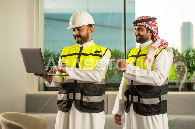 The concept of planning and execution, management of engineering projects, professional coordination within the work environment, a Saudi Gulf Arab engineer wearing a helmet and safety vest reviewing data on a laptop and discussing work steps with a colleague.