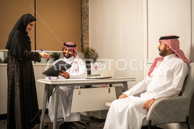 The concept of administrative organization in clinics, delivery and review of medical files, an Arab Gulf Saudi doctor wearing a white thobe and shemagh reviewing medical documents accompanied by his colleague.