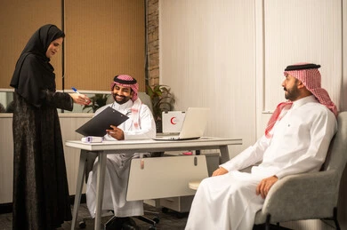 The concept of administrative organization in clinics, delivery and review of medical files, an Arab Gulf Saudi doctor wearing a white thobe and shemagh reviewing medical documents accompanied by his colleague.