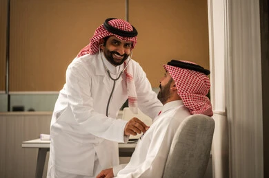 المتابعة الدورية لفحص نبضات القلب، مفهوم الطب والرعاية الصحية، قياس معدل ضربات القلب, طبيب عربي خليجي سعودي يرتدي المعطف الطبي يقوم باستخدام سماعه الفحص الطبية للمريض