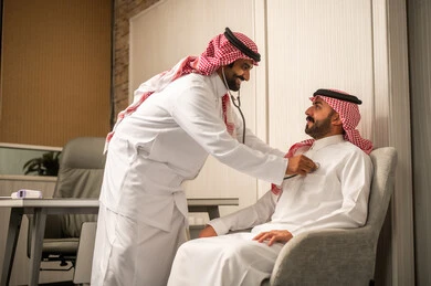 مفهوم الطب والرعاية الصحية،، قياس معدل ضربات القلب, المتابعة الدورية لفحص نبضات القلب, طبيب عربي خليجي سعودي يرتدي المعطف الطبي يقوم باستخدام سماعه الفحص الطبية للمريض