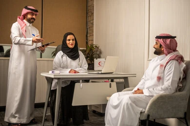 Medical examination and consultation session, medicine and healthcare, regular health follow-up, a Saudi Gulf Arab female doctor in a hijab wearing a medical coat discussing the patient's health condition with her colleague, writing and taking notes.