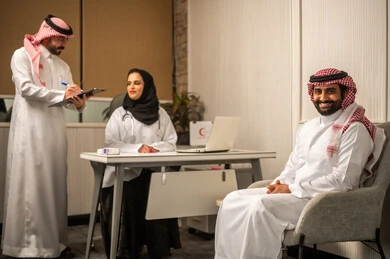 الطب والرعاية الصحية, جلسة فحص واستشارة طبية, المتابعة الصحية الدورية, طبيبة عربية خليجية سعودية محجبة ترتدي المعطف الطبي تناقش الحالة الصحية للمريض مع زميلها، كتابة و تدوين الملاحظات