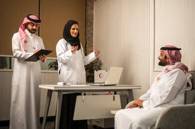 جلسة استشارة طبية داخل عيادة, طبيبة عربية خليجية سعودية محجبة ترتدي المعطف الطبي تناقش الحالة الصحية للمريض برفقة زميلها ، مفهوم الطب والرعاية الصحية، كتابة و تدوين الملاحظات