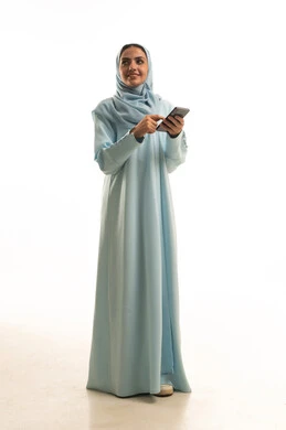 الدردشة مع الأهل والأصدقاء وتصفح مواقع التواصل الاجتماعي، استخدام الأجهزة التقنية الحديثة، بورترية لامراه عربيه خليجيه سعودية ترتدي العباءة و الحجاب تمسك الهاتف المحمول، ايماءات السعادة و السرور، الجسم بالطول الكامل، خلفية بيضاء