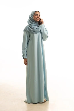 استخدام الأجهزة التقنية الحديثة في الحياة اليومية,التواصل مع العائلة والأصدقاء, مشاركة الأخبار والأحاديث الجيدة, بورتريه لامرأة عربية خليجية سعودية  محجبة ترتدي العباءة تمسك بيدها الهاتف المحمول,إجراء اتصال هاتفي,  الجسم بالطول الكامل، خلفية بيضاء