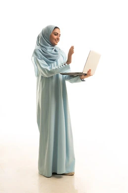 اجراء مكالمة فيديو،رفع كف اليد بتعابير التحية و السلام، ادارة العمل عن بعد، استخدام جهاز تقني حديث ومتطور، بورتريه لامرأة عربية خليجية سعودية محجبة ترتدي العباءة تعمل على جهاز الحاسوب المحمول, الجسم بالطول الكامل، خلفية بيضاء
