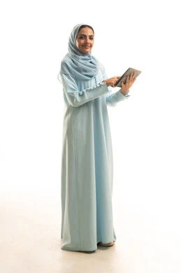 The use of advanced modern technology in professional life through a tablet, expressions and gestures of integration, a portrait of a young Arab Gulf Saudi woman wearing a hijab and abaya working on a tablet, full-body image, white background.