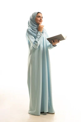 ايماءات التفكير فى شيء ما، مفهوم التعلم الذاتي، قضاء الوقت بالقراءة والتعلم والثقافة، بورتريه لامراة عربيه خليجيه سعودية ترتدي العباءة و الحجاب تقوم بمطالعة كتاب، الجسم بالطول الكامل، خلفية بيضاء