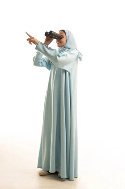 Referring to something, seeing distant things through a telescope, future planning for goals and ambitions, a portrait of a Saudi Arabian Gulf woman wearing a black abaya, looking through a telescope with gestures of happiness and joy, full-body, white background.