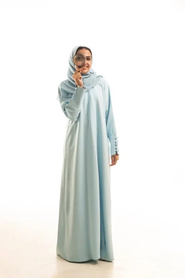 الفحص والإستكشاف والقراءة، مفهوم توضيح الصورة، بورتريه  لشابة عربية خليجية سعودية محجبة ترتدي العباءة تنظر من خلال العدسة المكبرة، التدقيق والتركيز وتكبير الاشياء, أدوات بصرية للرؤية عن قرب، الجسم بالطول الكامل، خلفية بيضاء