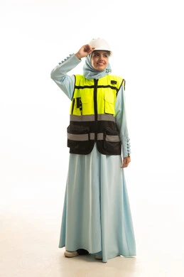 مفهوم ادارة المشاريع الهندسية، الوقوف بايماءت الثقة, وظائف ومهن نسائية, العمل في القطاع الهندسي, بورتريه لمهندسة معمارية عربية خليجية سعودية ترتدي خوذة الحماية والسترة تنظر الى الكاميرا بتعابير السرور، الجسم بالطول الكامل، خلفية بيضاء