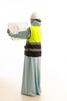 Working in the field of engineering, supervising engineering project plans, the concept of architectural constructions, a portrait from behind of a Saudi Arabian Gulf female architect wearing an abaya, a jacket, and a safety helmet holding a construction plan in her hand, a profession and job for women in the Kingdom of Saudi Arabia, white background.