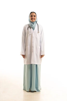 Standing upright and looking confidently at the camera, working in the healthcare sector, a portrait of a Saudi Gulf Arab female doctor wearing a medical coat looking with expressions of joy, providing therapeutic services and medical examinations for patients, Saudi professions and jobs, gestures of happiness and joy, full-body, white background.