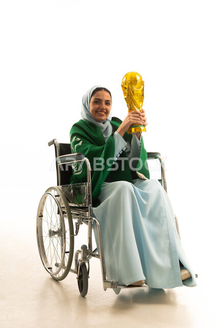 Saudi National Day is September 23, the participation of Saudi women in sports activities and matches, encouraging clubs and national teams, a portrait of a young Arab Saudi Gulf woman wearing an abaya and the Saudi flag sitting in a wheelchair holding the cup, raising her hand with gestures of excitement for the victory and triumph of her favorite team, white background.