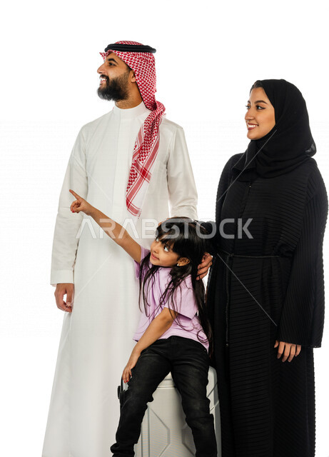 بورتريه لعائلة عربية سعودية خليجية سعيدة بإنتظار رحلتها ، ينظرون تجاه مكان ما ، تجلس الطفلة على حقيبة السفر و تشير تجاه مكان ما ، سفر و سياحة ترفيهية ، رحلة عائلية سعيدة ، مفهوم الأسرة السعيدة ، قضاء أوقات عائلية ممتعة