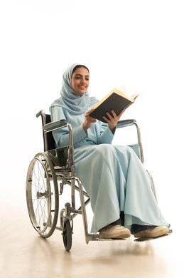 تنمية المهارات الفنية والذهنية، ثقافة التعلم الذاتي، بورتريه لامراه عربية خليجية سعودية من ذوي الاحتياجات الخاصة محجبة ترتدي العباءة تجلس على كرسي متحرك تقوم بالمطالعة وقراءة الكتب المفيده، خلفية بيضاء