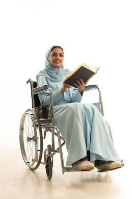 ثقافة التعلم الذاتي، تنمية المهارات الفنية والذهنية، بورتريه لامراه عربية خليجية سعودية من ذوي الاحتياجات الخاصة محجبة ترتدي العباءة تجلس على كرسي متحرك تقوم بالمطالعة وقراءة الكتب المفيده، خلفية بيضاء
