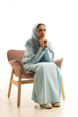 التمعن والتركيز والتخطيط للمستقبل، محاولة إيجاد حل لشيء ما، إيماءات الحيرة والقلق, النظر بشرود إلى مكان ما, بورترية لإمراة عربية سعودية خليجية محجبة ترتدي العباءة تجلس على كرسي تضع يدها على ذقنها وتنظر بتفكير وتأمل، خلفية بيضاء