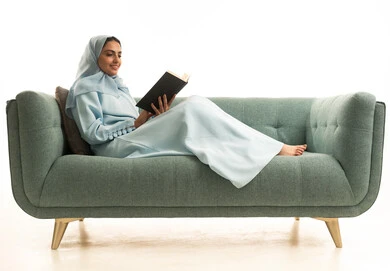 كتب وروايات هادفه ومسليه، مفهوم الشغف بالقراءة، ممارسة هواية المطالعة, بورتريه لامراة عربية خليجية سعودية محجبة ترتدي العباءة تجلس على  الاريكة تقوم بقراءه كتاب، التعلم والتثقيف من خلال قراءه الكتب الهادفه، خلفيه بيضاء