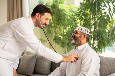 المراقبة الدورية لمعدل نبضات القلب, مفهوم الطب والرعاية الصحية, طبيب عربي خليجي سعودي يرتدي المعطف الطبي يقوم باستخدام سماعه الفحص الطبية لمريض كبير بالسن
