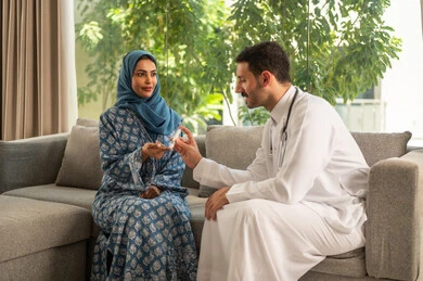 المتابعة الدورية لمرضى داء السكري, الفحوصات الطبية السريعة لمعرفة نسبة السكر في الدم، استخدام الأجهزة الالكترونية للتحاليل المنزلية، شابة سعودية مصابة بحالة مرضية مزمنة, طبيب عربي خليجي سعودي يرتدي المعطف الطبي يقوم بوخز اصبع امرأة