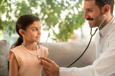 Providing healthcare and caring for patients' health, working in the health sector in Saudi Arabia, a close-up image of an Arab Gulf Saudi doctor wearing traditional attire examining a girl with an otoscope at home, using a stethoscope to listen to heartbeats.