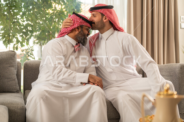 الحصول على الرضى، مفهوم الحب والحنان، دور الأب في حياه الأبناء، رجل عربي خليجي سعودي يرتدي الثوب التقليدي والشماغ يقوم بتقبيل رأس والده، قضاء وقت ممتع ومسلي، ايماءات السعادة والسرور، اجواء اسرية مليئة بالفرح