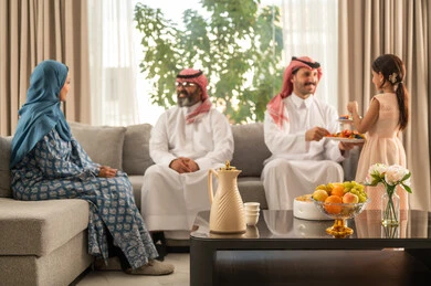 ضيافة العيد وتقديم الحلوى، مناقشات و حوارات اسرية ، فرحة وبهجة الابناء في ايام العيد السعيد, التجمعات والزيارات الاسرية في الأعياد والمناسبات الاسلامية, رجل عربي خليجي سعودي يرتدي الثوب التقليدي يجلس مع أحفاده بإيماءات الفرح والسرور, حسن استقبال وإكرام الضيف، صلة الرحم والترابط الاسري