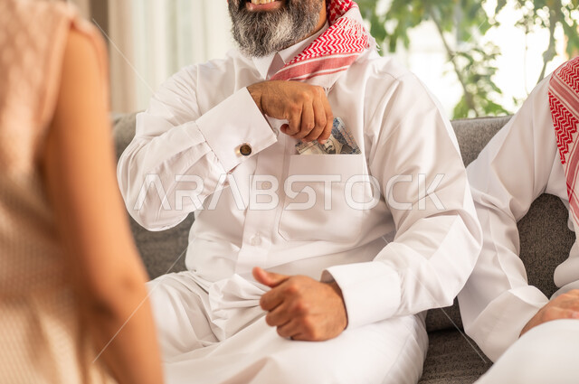 تقديم العيدية في العيد، مفهوم الحب والحنان، دور الأب في حياه الأبناء، جد عربي خليجي سعودي يرتدي الثوب التقليدي والشماغ  يعطي الفلوس لحفيدته، عادات وتقاليد الاعياد والمناسبات الدينية، ايماءات السعادة والسرور، اجواء اسرية مليئة بالفرح