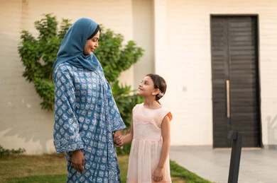 شاليه ومنتجع ترفيهي في المملكة، مفهوم الترابط الأسري المبني على المحبه، الاستمتاع بالإجازة الصيفية برفقة العائلة، قضاء وقت ممتع ومنعش في فصل الصيف، ام عربية خليجية سعودية محجبة ترتدي العباءة تنظر الى ابنتها بايماءات السعادة و السرور