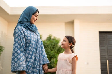 مفهوم الترابط الأسري المبني على المحبه، الاستمتاع بالإجازة الصيفية برفقة العائلة، شاليه ومنتجع ترفيهي في المملكة، قضاء وقت ممتع ومنعش في فصل الصيف، ام عربية خليجية سعودية محجبة ترتدي العباءة تنظر الى ابنتها بايماءات السعادة و السرور