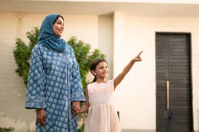 قضاء وقت ممتع ومنعش في فصل الصيف،  فتاه عربيه خليجية سعودية ترتدي فستان تقف مع والدتها في الهواء الطلق و تقوم بالاشارة الى شيء ما، شاليه ومنتجع ترفيهي في المملكة، مفهوم الترابط الأسري المبني على المحبه، الاستمتاع بالإجازة الصيفية برفقة العائلة