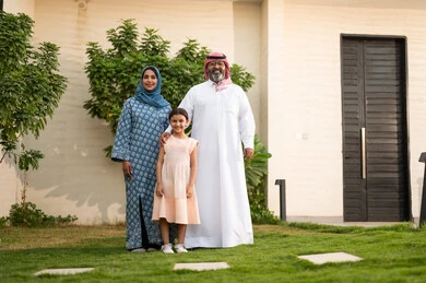 Sharing fun-filled moments with children, maintaining family bonds, caring for and attending to children, playing, having fun, and enjoying leisure time with the family outdoors; a Saudi Arabian Gulf couple playing in the park with their daughter, beaming with happiness.