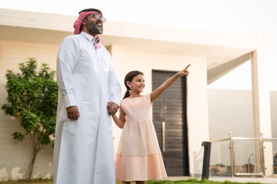 الاشارة الى شيء ما, قضاء أوقات ممتعه مع الأبناء، رجل عربي خليجي سعودي يرتدي الثوب التقليدي والشماغ يلعب في الحديقة مع ابنته بإيماءات السعادة، المحافظة على الترابط الأسري، الاعتناء والاهتمام بالاولاد