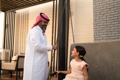 الإستمتاع باللعب في يوم مشمس، التأرجح على الأرجوحه, قضاء وقت ممتع في الخارج، فتاة عربيه سعوديه خليجيه مبتسمة تلعب في المنتزه بتعابير السرور والسعادة برفقة والدها