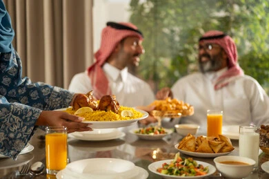 اجتماع الأهل ومشاركة الطعام على مائده الإفطار، المأكولات والمقبلات الرمضانيه المتنوعه والشهية، عائله عربيه خليجيه سعودية تقوم بتناول الفطور، امراه عربيه خليجيه سعودية ترتدي العباءة تقوم بتقديم الطعام , حسن الضيافة وإكرام الأخرين