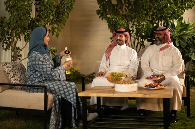 إمرأة عربية خليجية سعودية ترتدي العباءة والحجاب تقوم بصب القهوة الخليجية وتقديمها للضيوف ، تقديم المشروبات الساخنة العربية الأصيلة في الأعياد، كرم الضيافة وحسن الاستقبال في السعودية، أصالة عادات وتقاليد المجتمع السعودي في المناسبات الاسلامية