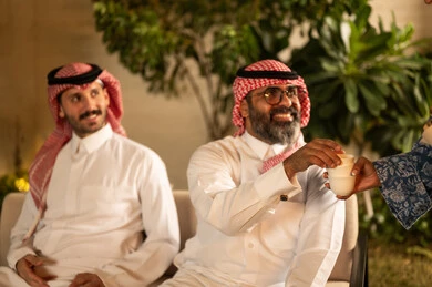 تقديم القهوة العربية في المناسبات الاسلامية,  صورة مقربة ليد امراة عربية خليجية سعودية  تقوم بتقديم فنجان القهوة, الاستمتاع بالمشروبات الساخنة, حسن الاستقبال واكرام الضيف، صلة الرحم والترابط الاسري، التجمعات والزيارات الاسرية في الأعياد والمناسبات الاسلامية