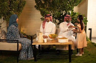أجواء المجتمع السعودي في المناسبات والأعياد السعيدة، بهجة وفرحة العيد المبارك, العادات والتقاليد والقيام بالزيارات العائلية, مفهوم اكرام الضيف وحسن الاستقبال، ضيافة و حلوي العيد،  رجل عربي خليجي سعودي يرتدي الثوب التقليدي يجلس مع أحفاده بإيماءات الفرح والسرور