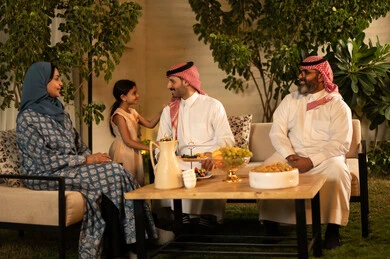 الزيارات العائلية والتجمعات خلال الأعياد والمناسبات الإسلامية، صلة الرحم والترابط الاسري, عائلة عربية خليجية سعودية تجلس في الخارج بإيماءات الفرح والسرور، ضيافة وحلوى العيد، حسن استقبال وإكرام الضيف, فرحة وبهجة الابناء في ايام العيد السعيد