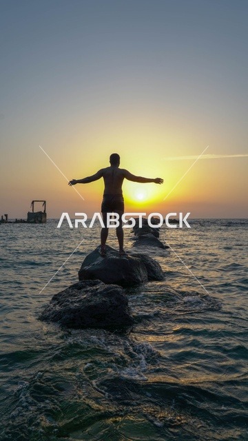 الاستمتاع بالأجواء الهادئة في وقت غروب الشمس فوق البحر الأحمر, رجل في البحر، البيئه الطبيعيه لكورنيش جده السياحي,  أماكن السياحه الترفيهيه في مدينه جده في المملكة العربيه السعوديه, معالم سياحيه مشهورة,  واجهة جدة البحرية وهدوء البحر