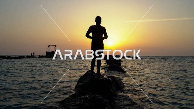 رجل في البحر، الاستمتاع بالأجواء الهادئة في وقت غروب الشمس فوق البحر الأحمر, البيئه الطبيعيه لكورنيش جده السياحي,  أماكن السياحه الترفيهيه في مدينه جده في المملكة العربيه السعوديه, معالم سياحيه مشهورة,  واجهة جدة البحرية وهدوء البحر