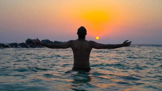 Enjoying the calm atmosphere at sunset over the Red Sea, a man in the sea, the natural environment of Jeddah's tourist corniche, recreational tourist spots in the city of Jeddah in the Kingdom of Saudi Arabia, famous tourist landmarks, Jeddah's waterfront and the tranquility of the sea.