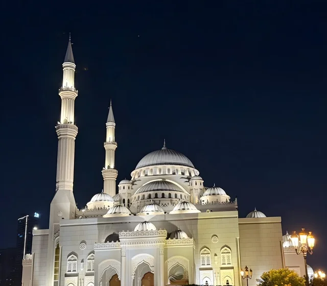 The Noor Mosque in the Emirate of Sharjah is a prominent Islamic landmark in the United Arab Emirates, featuring elegant Islamic architecture illuminated at night, with white domes and towering minarets in a serene spiritual scene.