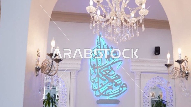 The Omar bin Al-Jamouh Mosque in Ibn Khaldun neighborhood (Al-Muraykabat) in the city of Dammam is a religious Islamic mosque in the Kingdom of Saudi Arabia, featuring a small indoor bird garden, chandeliers and hanging lights on the ceiling, green plants inside the mosque, and interior decoration in the Islamic style.