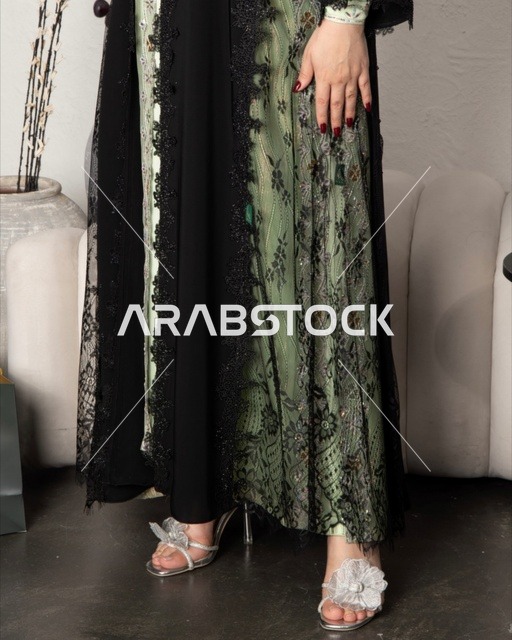 Modern women's fashion, the concept of beauty, elegance, and attention to appearance, a Gulf Arab Saudi woman wearing a black embroidered abaya made of chiffon and lace in a modern style.