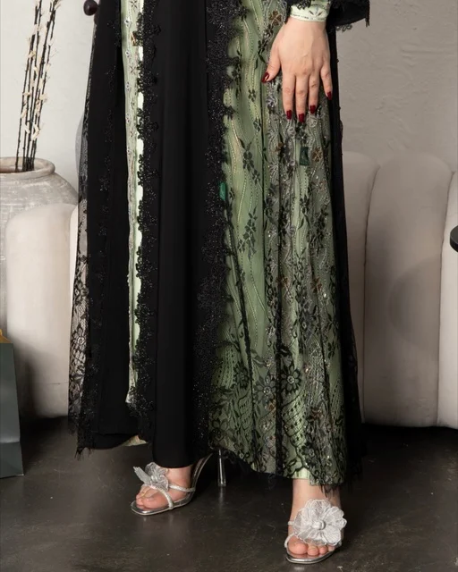 Modern women's fashion, the concept of beauty, elegance, and attention to appearance, a Gulf Arab Saudi woman wearing a black embroidered abaya made of chiffon and lace in a modern style.