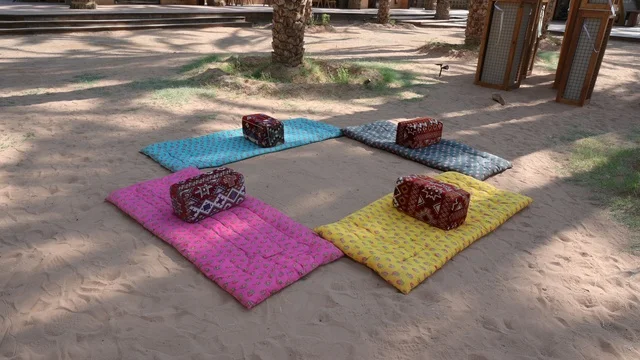 منطقة جلوس خارجية تقليدية ملونة على الرمل في مزارع العلا، قرية العلا التراثية شمال غرب المملكة العربية السعودية، السياحة في السعودية، المعالم التاريخية والآثرية القديمة في بلدة العلا القديمة